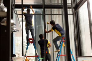 Arbeiter tragen im Sommer getönte Schicht auf Glasfenster auf