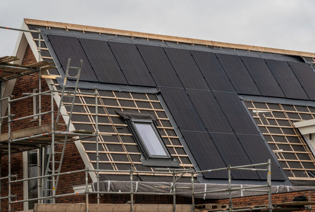 Ein Haus wird gebaut und auf dem Dach ist eine Photovoltaik Anlage während an dem Haus noch gebaut wird