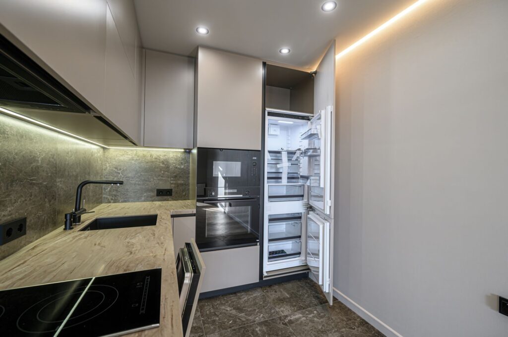 Offene Designküche mit geöffnetem Getränkekühlschrank und Holzarbeitsplatte